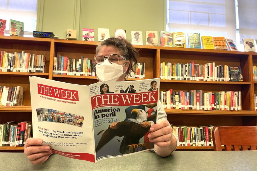 Director of Library Services & Research Program Mrs. Nora Murphy reads a copy of  The Week to learn about current events.