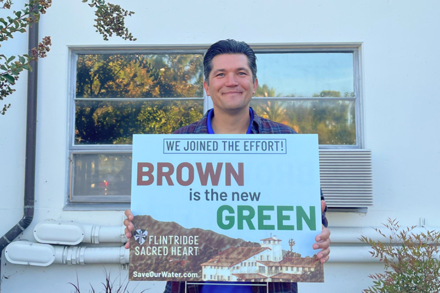 Mr. Eric Pivovaroff holds the sign “Brown is the New Green,” which is the new effort Sacred Heart has joined to help conserve water on campus.