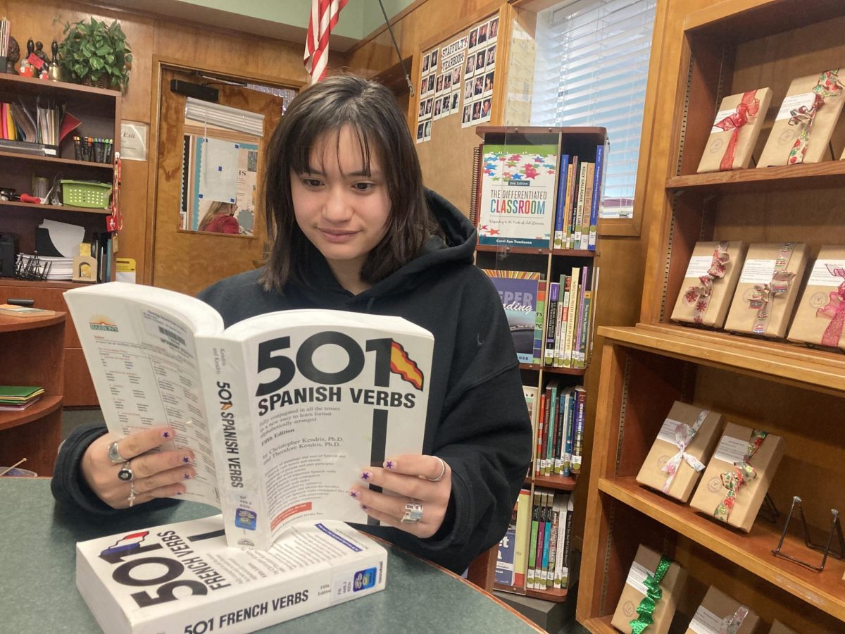 Ava Barraza ‘24 practices her verbs with French and Spanish language books in the library. Photo by Claudia Lee ‘24. 
