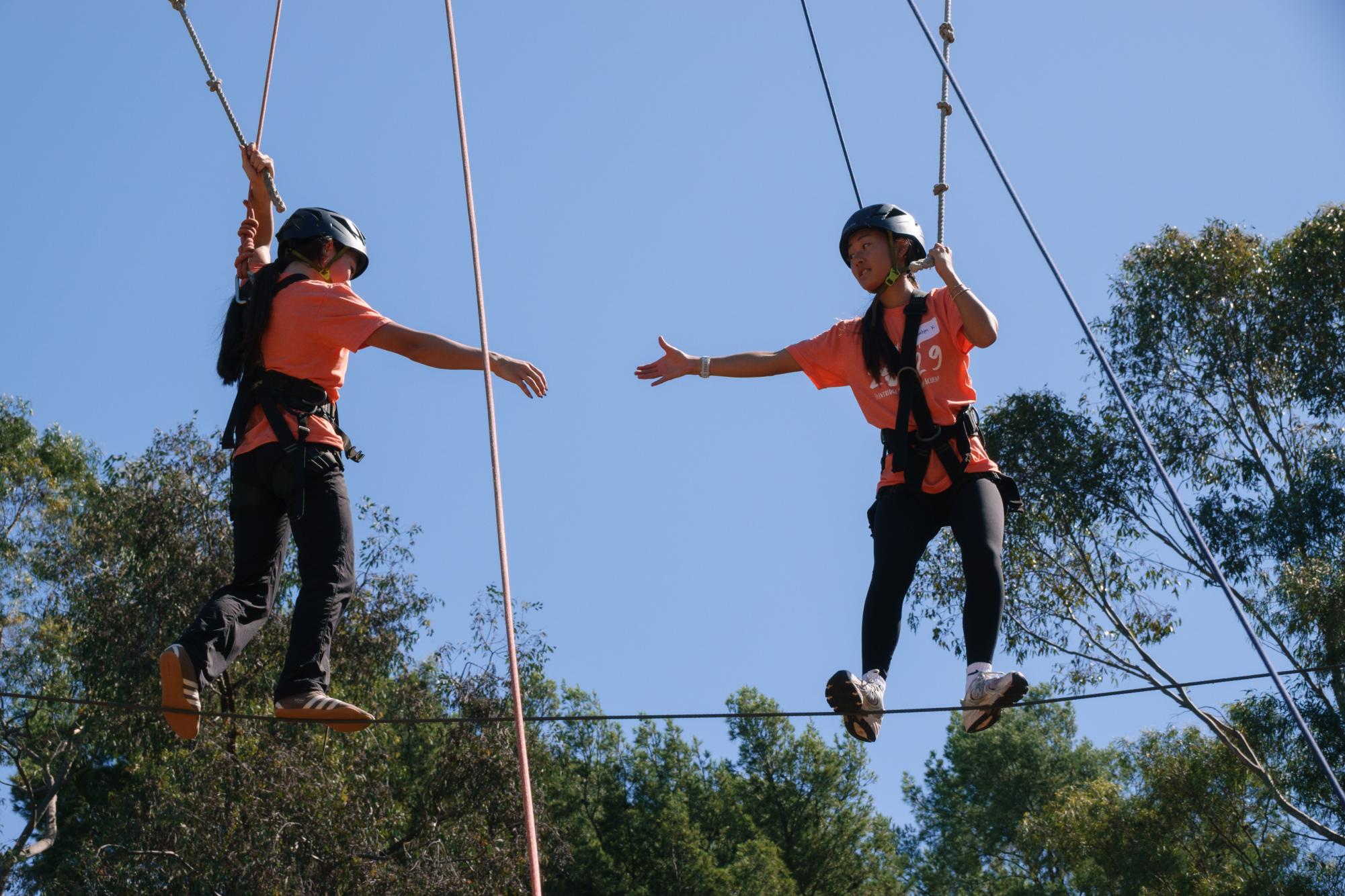 Two Tologs working as a team to complete the ropes course.