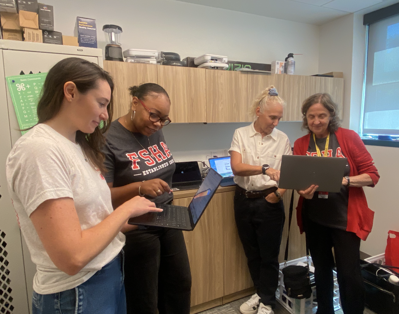 Faculty members Dr. Bray Kress, Ms. Adkins-Williams, Ms. Desmond and Mrs. Sakarati work on laptops at the Help Desk.